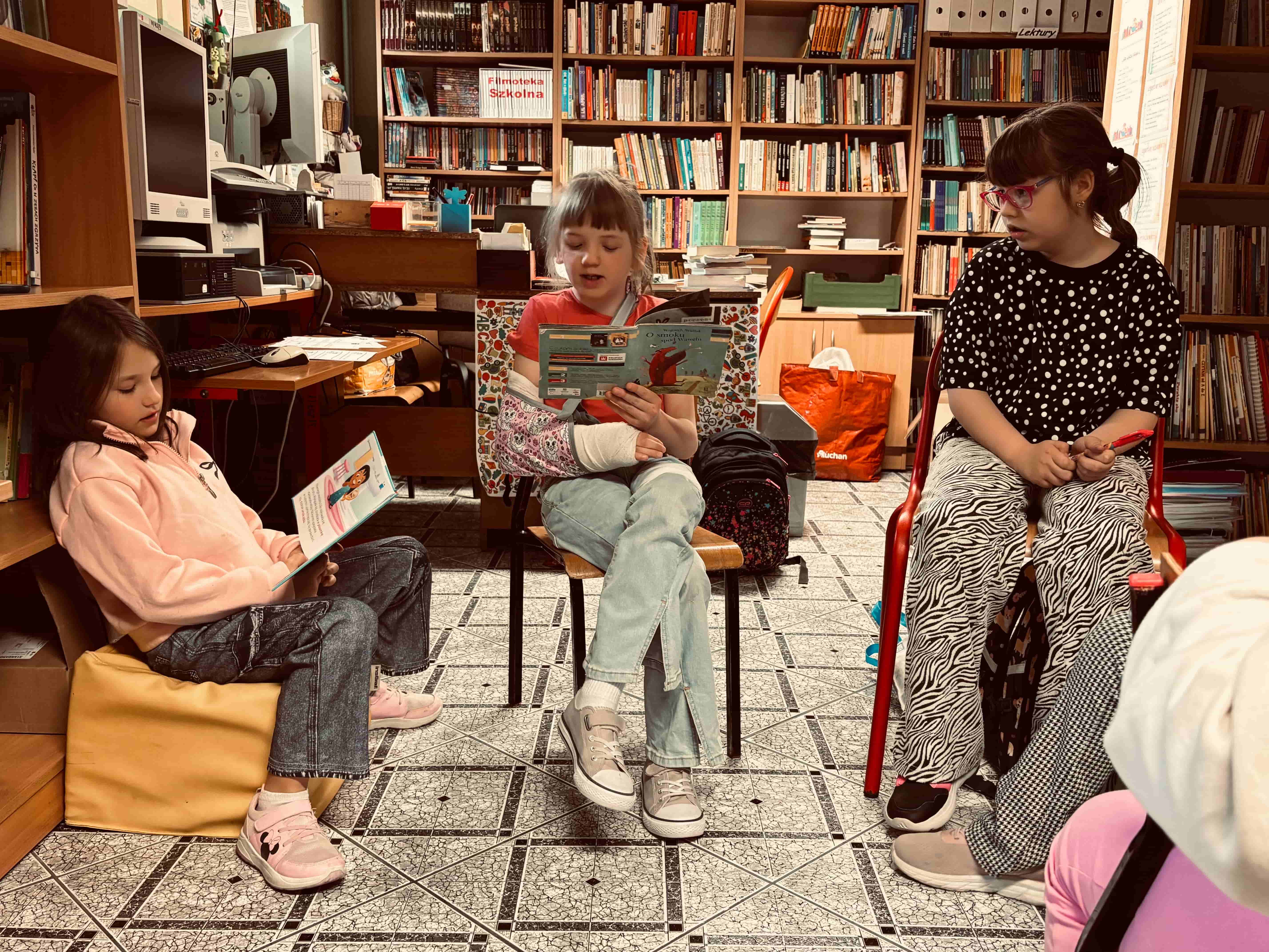 Uczennica czyta na głos ksiązkę w bibliotece