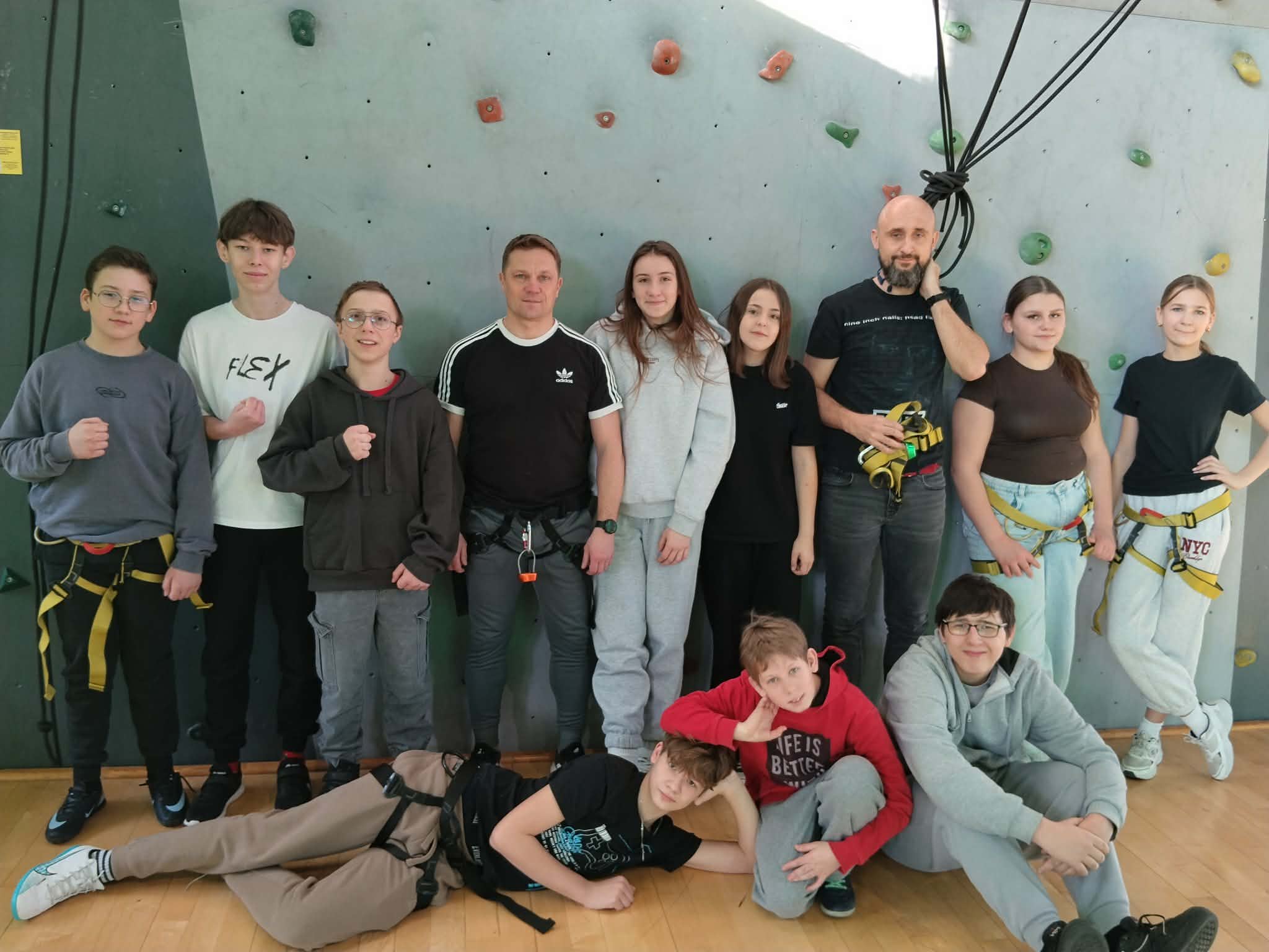 Grupa uczniów przed ścianką wspianczkową z nauczycielem i instruktorem