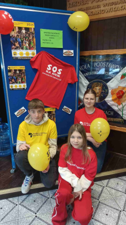 Wolontariusze przed gazetką na temat akcji 'Pączek dla Afryki', zdjęcie 1 z 5