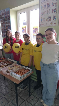 Uczniowie za ladą z mufinkami i pączkami podczas akcji charytatywnej na rzecz Afryki w Waganowicach, zdjęcie 3 z 5