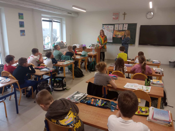 Uczniowie siedzą w ławkach, słuchają opowiadania bibliotekarki podczas warsztatów, zdjęcie 1 z 5