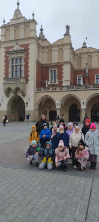 Grupa uczniów stoi przed Sukiennicami w Krakowie podczas wycieczki szkolnej, zdjęcie 1 z 4