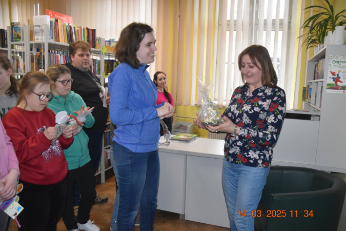 Wręczanie drobnych prezentów uczniom przez organizatorów warsztatów w bibliotece, zdjęcie 4 z 5