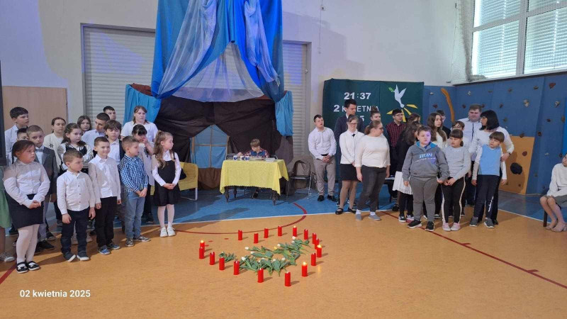 Uczniowie w skupieniu uczestniczą w akademii poświęconej Janowi Pawłowi II na sali gimnastycznej, zdjęcie 7 z 7