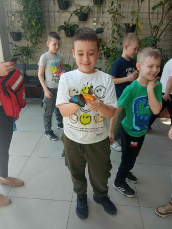 Grupa uczniów bierze udział w warsztatach przyrodniczych w motylarni, otoczona przez egzotyczne motyle, zdjęcie 5 z 5