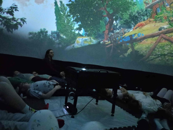 Uczniowie siedzący w kinie sferycznym we wnętrzu kopuły, podczas seansu filmu 'Przygody Khrumka' wyświetlanego nad głowami, zdjęcie 1 z 5