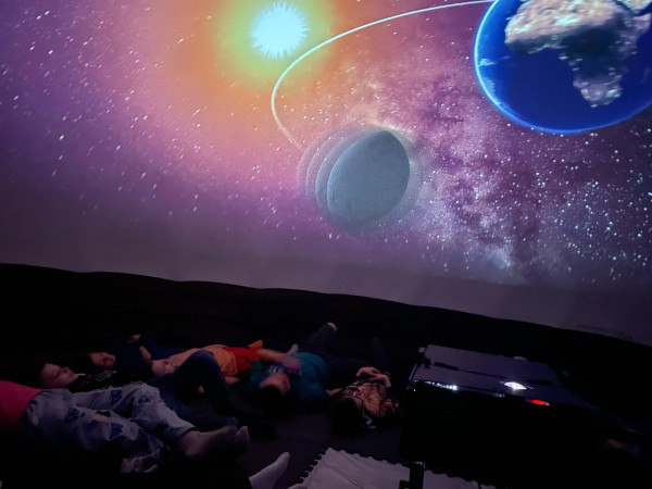 Grupa uczniów oglądających seans filmowy w mobilnym kinie sferycznym, zdjęcie 3 z 5