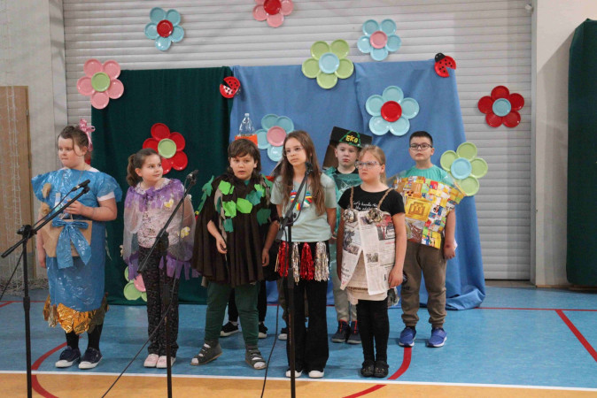 Uczniowie w kolorowych strojach występują na scenie podczas szkolnego festiwalu ekologicznego, zdjęcie 4 z 5