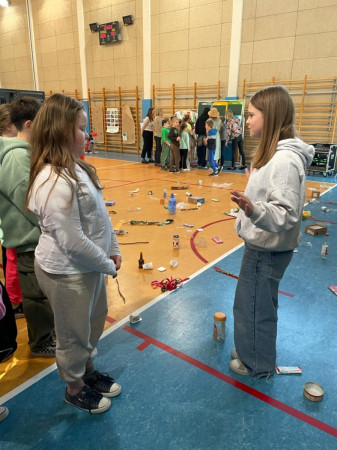 Młodsi uczniowie słuchają starszych podczas zajęć o segregacji odpadów na sali gimnastycznej, zdjęcie 5 z 5