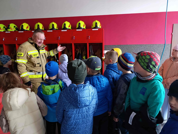 Uczniowie w skupieniu słuchają opowieści o pracy strażaka w remizie, zdjęcie 3 z 5