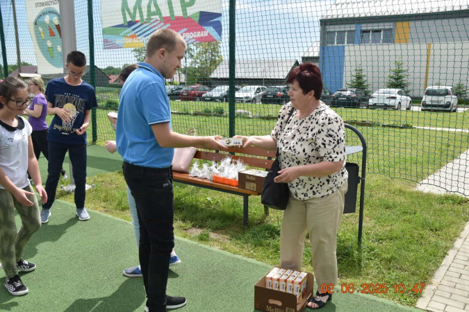 Senior wręcza upominek uczniowi podczas spotkania z okazji Dnia Dziecka, zdjęcie 1 z 5
