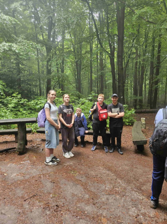 Pięcioro uczniów w plenerze leśnym odpoczywa przy drewnianej ławce w górach Świętokrzyskich, zdjęcie 4 z 5