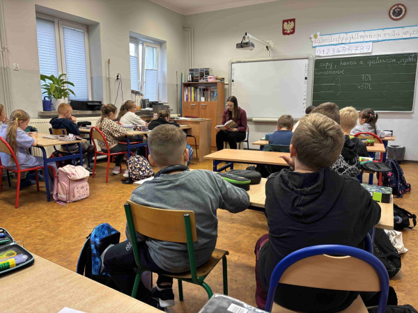 Nauczyciel czyta uczniom książkę podczas lekcji z okazji Ogólnopolskiego Dnia Głośnego Czytania, zdjęcie 1 z 5