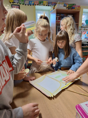 Dzieci rozwiązujące zadania przed pasowaniem na czytelnika w bibliotece, zdjęcie 2 z 5