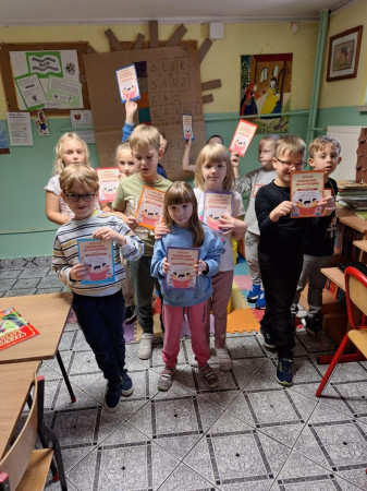 Uczniowie z dyplomami po pasowaniu na czytelnika, stojący w bibliotece, zdjęcie 4 z 5