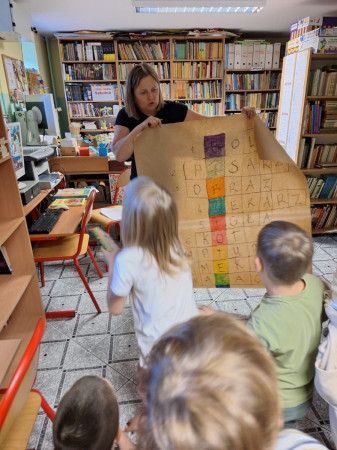 Pani bibliotekarka trzymająca wykonaną przez dzieci krzyżówkę w bibliotece, zdjęcie 5 z 5