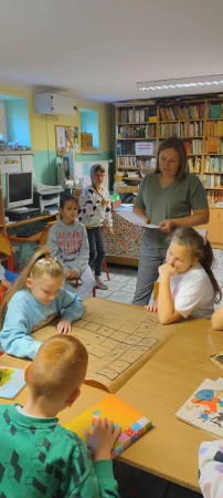 Grupa uczniów pracuje wspólnie przy stoliku w bibliotece, zdjęcie 3 z 4