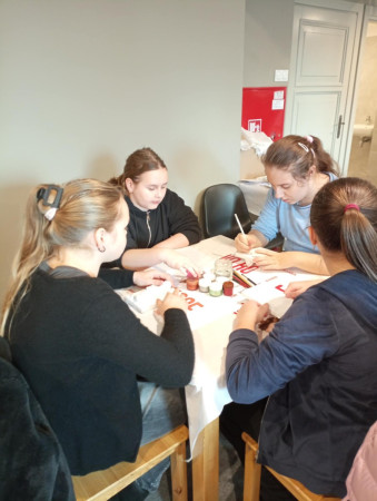 Uczennice przy stolikach ozdabiają gipsowe odlewy przedstawiające olkuskiego gwarka, zdjęcie 3 z 5