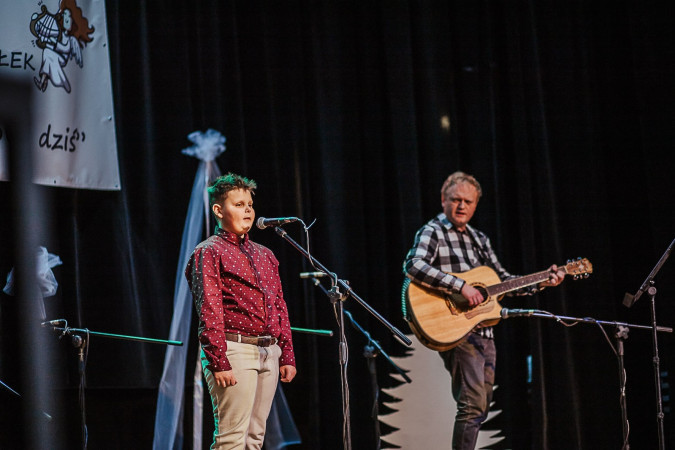 Występ chłopca z muzykiem na scenie podczas Międzyszkolnego Konkursu Kolęd i Pastorałek, zdjęcie 1 z 5