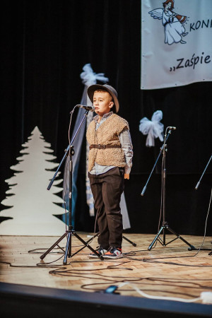 Uczeń w stroju pasterza występuje na scenie podczas Międzyszkolnego Konkursu Kolęd i Pastorałek, zdjęcie 5 z 5