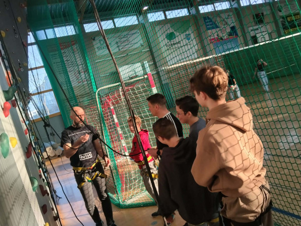 Grupa uczniów słucha instruktora przed ścianką wspinaczkową, zdjęcie 4 z 5
