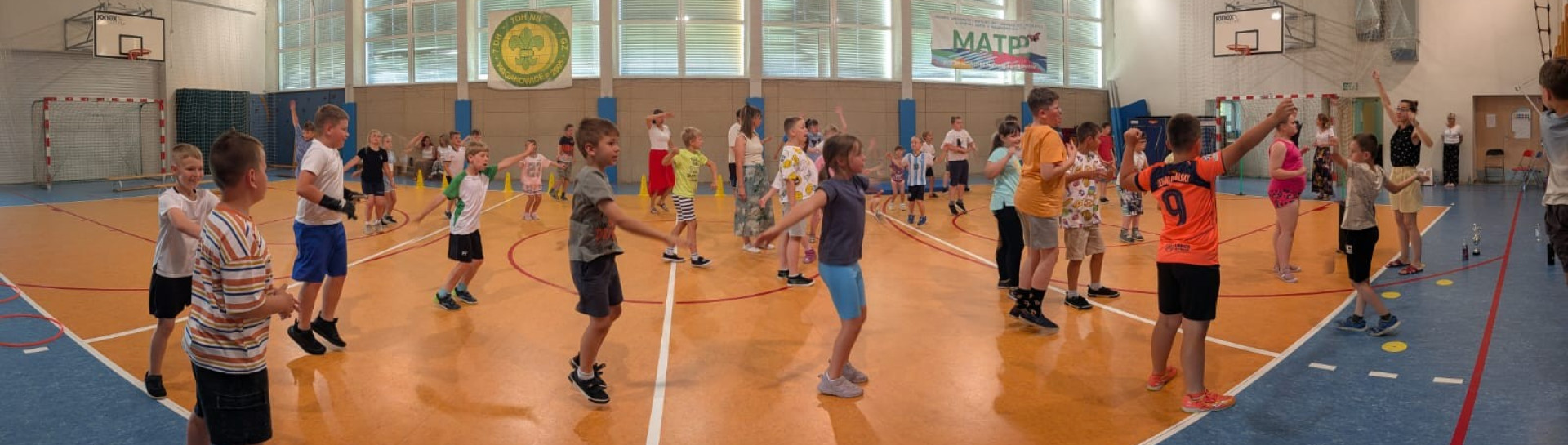 Uczniowie wykonują wspólne ćwiczenia na sali gimnastycznej