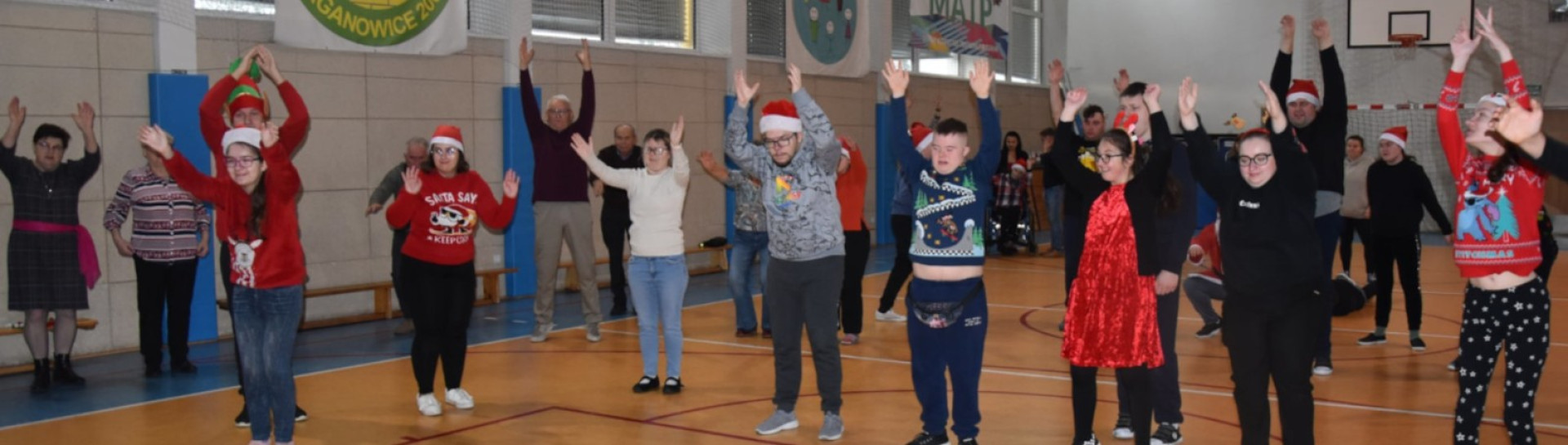 Uczestnicy spotkania wspólnie bawią się, podnosząc ręce podczas zabaw ruchowych
