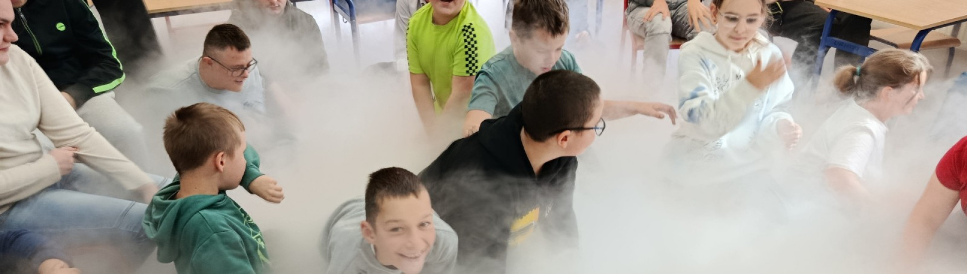 Uczniowie podczas warsztatów chemicznych w klasie wypełnionej sztuczną mgłą
