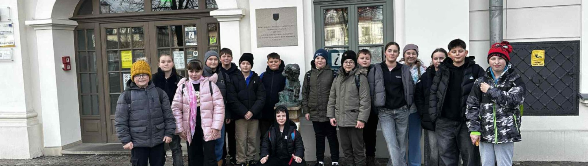 Grupa uczniów stoi przed wejściem na podziemną trasę edukacyjną „Podziemny Olkusz”