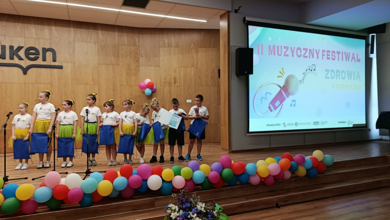 Uczniowie grupy wokalnej Promyczki pozują do wspólnego zdjęcia po występie podczas II Festiwalu Zdrowia, zdjęcie 1 z 5
