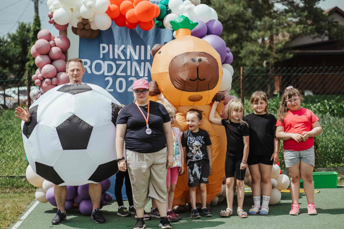 Uczniowie pozują przy ściance fotograficznej z osobami w kostiumach maskotek, zdjęcie 7 z 12